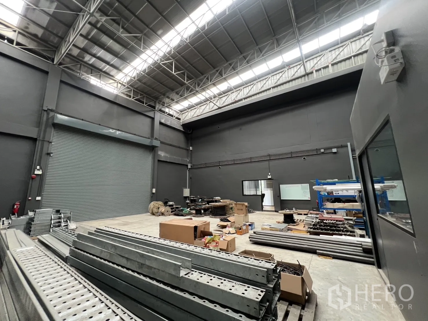 คลังสินค้า ขายในLat Krabang, Bangkok - ภายในโกดังเพดานสูง มีสกายไลท์ พื้นคอนกรีต และวัสดุจัดเก็บ.