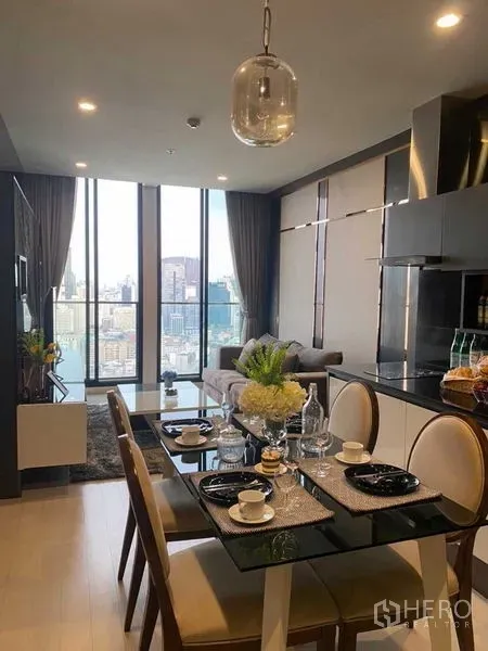 Condominium for sale in Pathum Wan, Bangkok - Open-plan dining and sleek kitchen facing tall windows with city views.