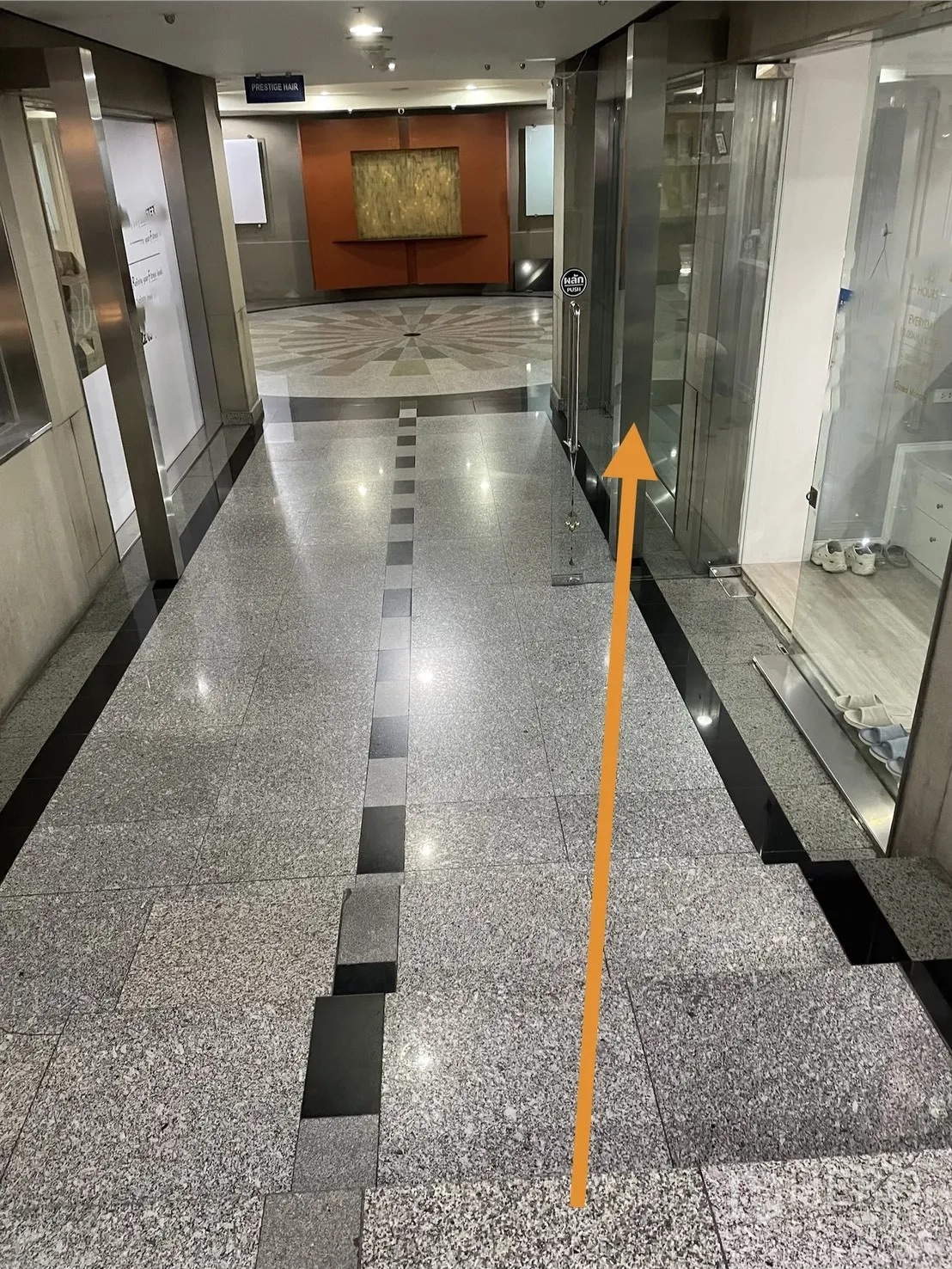 Retail Space for rent in Watthana, Bangkok - Polished stone corridor of the commercial building with neighboring shopfronts and ceiling lights.