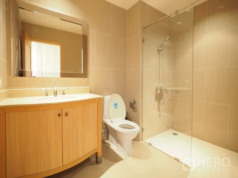 Condominium for rent in Sathon, Bangkok - Contemporary bathroom with glass-enclosed shower, vanity cabinet and neutral tile finishes.
