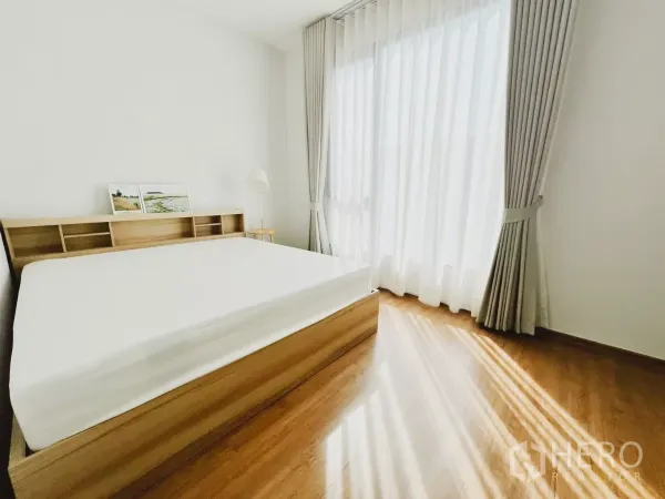 Townhouse for rent in Bang Phli, Samut Prakan - Sunlit master bedroom with wooden bedframe, floor-to-ceiling curtains and warm wood floors.