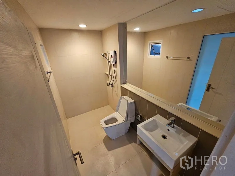 Townhouse for rent in Wang Thonglang, Bangkok - Modern bathroom with walk-in shower, wall-mounted sink, toilet, and recessed lighting.