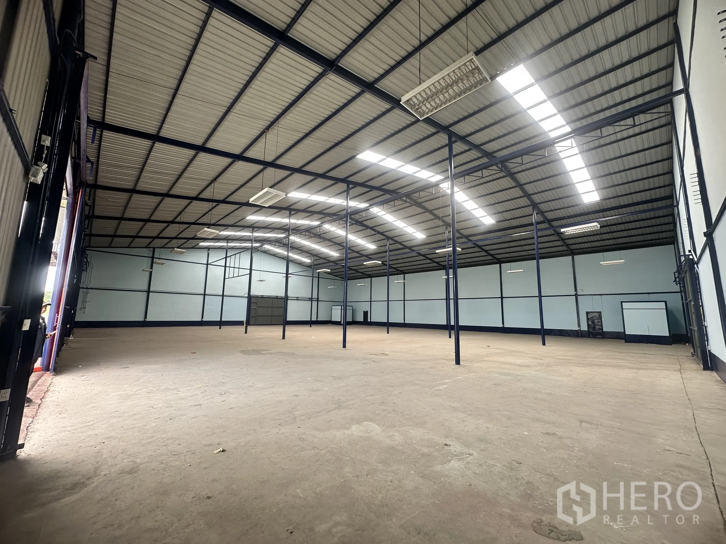仓库 for rent in Lat Krabang, Bangkok - 室内朝向装卸口的视角，可见高大的卷闸门与混凝土地面。