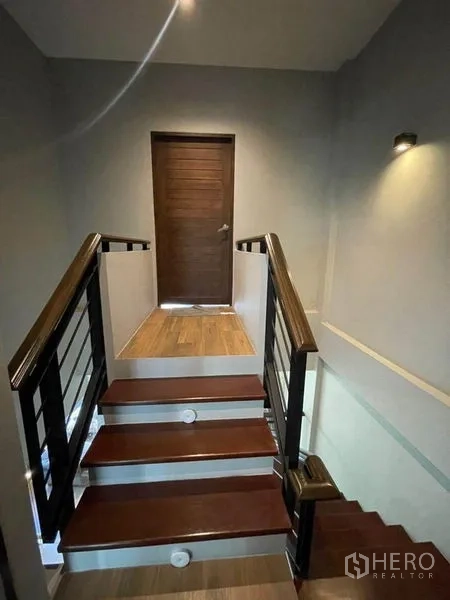 ทาวน์เฮาส์ ขายในBang Phli, Samut Prakan - ชานพักบันไดพื้นไม้ ราวเหล็ก ไฟติดผนัง และประตูห้องนอนด้านบน.