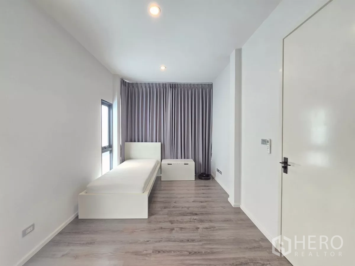 Detached House for rent in Prawet, Bangkok - Long single bedroom with wood floors, tall curtains and a side window.