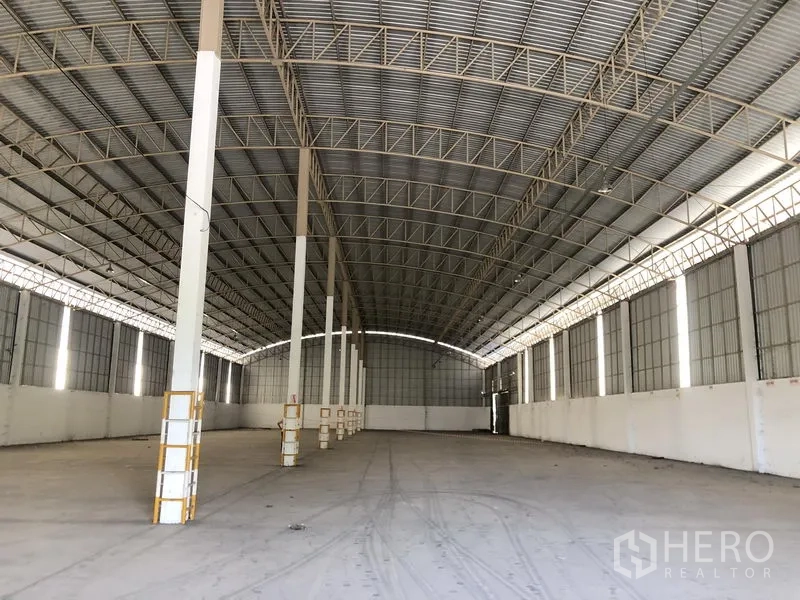 货栈 出租在Phan Thong, Chon Buri - 仓库内部宽敞，高耸钢桁架拱顶与大面积混凝土地面。