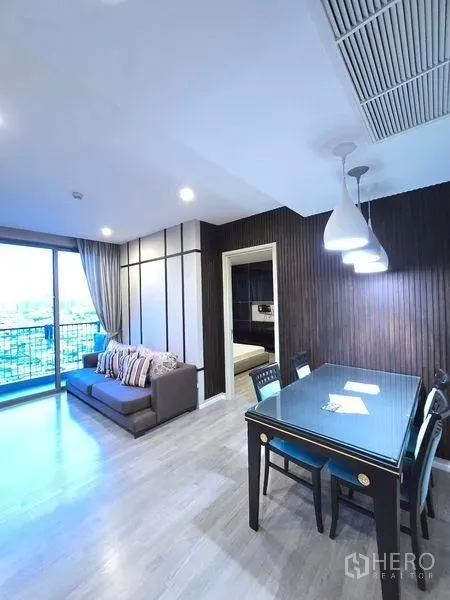Condominium for rent - Open-plan living and dining area with sofa, pendant lights and a balcony overlooking the city.