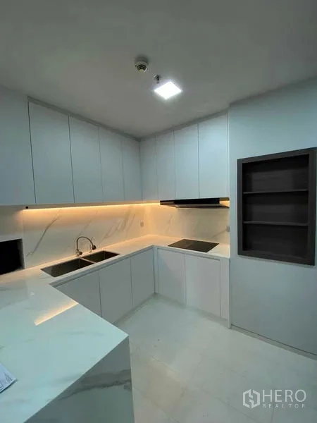 คอนโด ให้เช่าหรือขายในKhlong Toei, Bangkok - ครัวรูปตัว U เรียบหรู มีอ่างล้างจานคู่ เตาอินดักชัน และตู้เก็บของเต็มผนัง