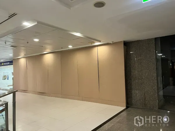 Retail Space for rent - Mall corridor frontage with wide hoarding wall, tiled floors and recessed lighting, showing prime shopfront visibility.