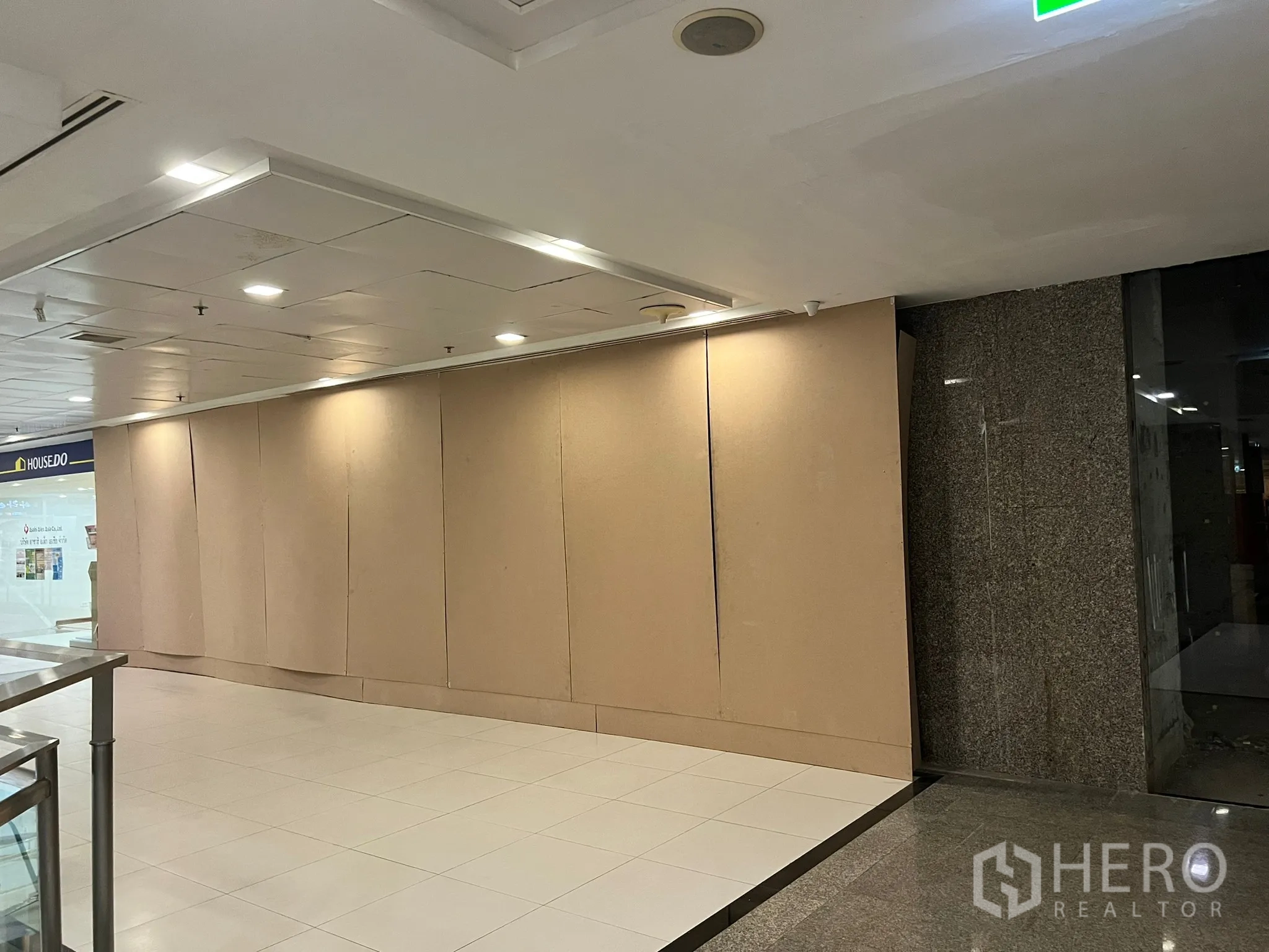 Retail Space for rent - Mall corridor frontage with wide hoarding wall, tiled floors and recessed lighting, showing prime shopfront visibility.
