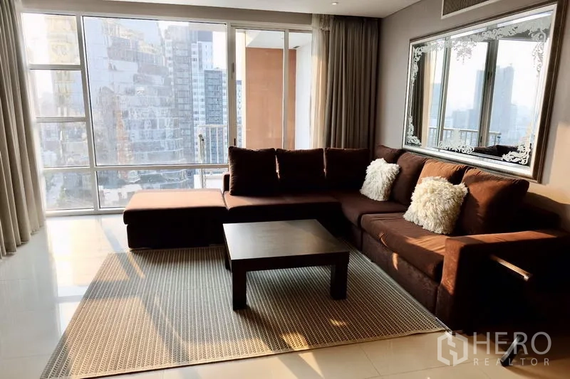 Condominium for rent in Watthana, Bangkok - Bright living room with brown sectional sofa, coffee table and floor-to-ceiling city-view windows.