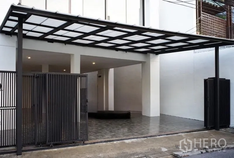 带办公室的家 出租或出售在Watthana, Bangkok - 带顶车棚，黑色金属大门与瓷砖车道。