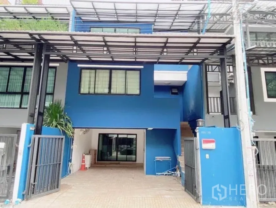 Townhouse for rent in Wang Thonglang, Bangkok - Blue multi-storey townhouse exterior with gated covered carport and metal awning in Wang Thonglang, Bangkok.