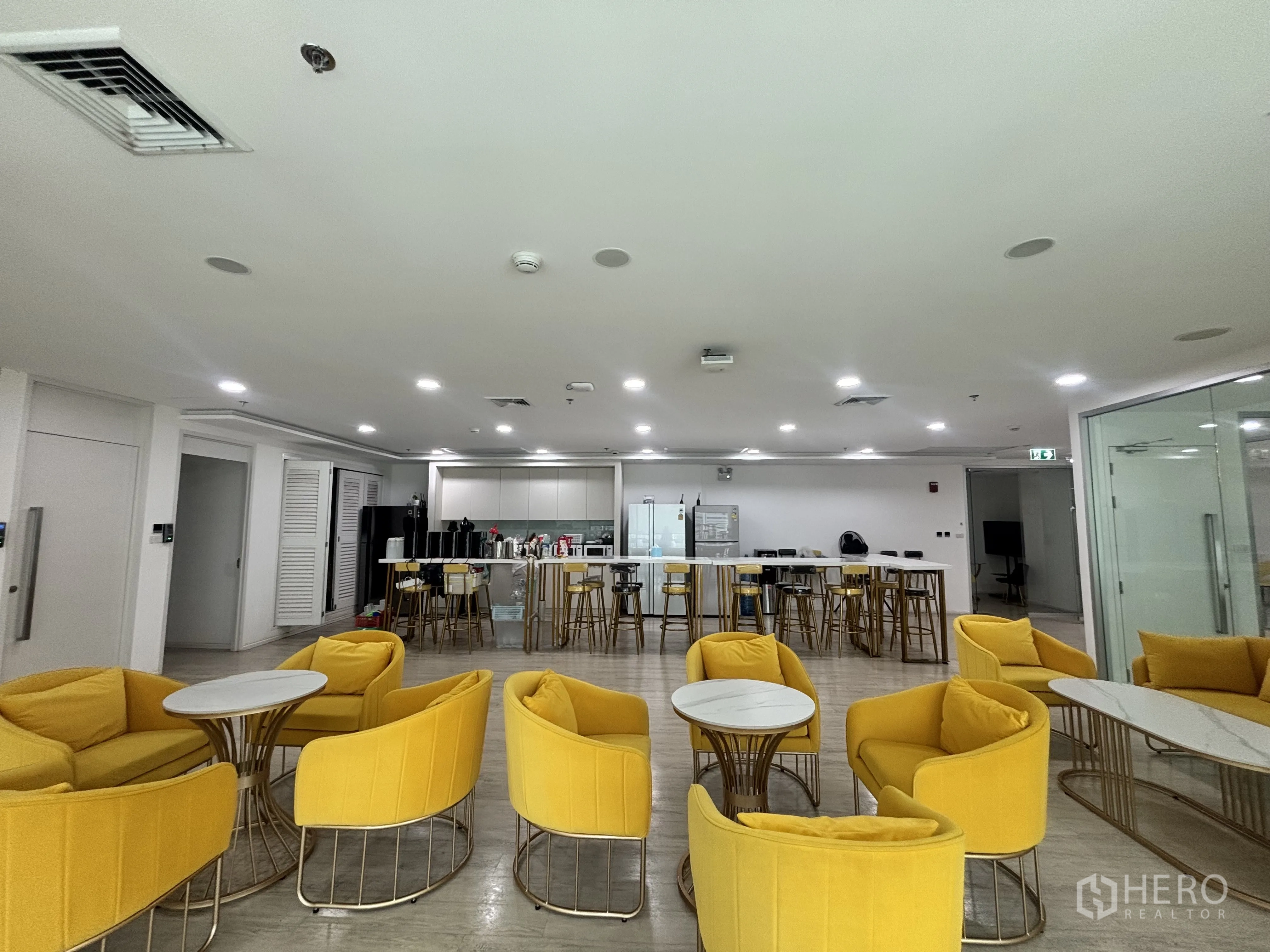 办公空间 for rent in Din Daeng, Bangkok - 大型茶水间与休闲区，黄色座椅和中央厨房岛台。