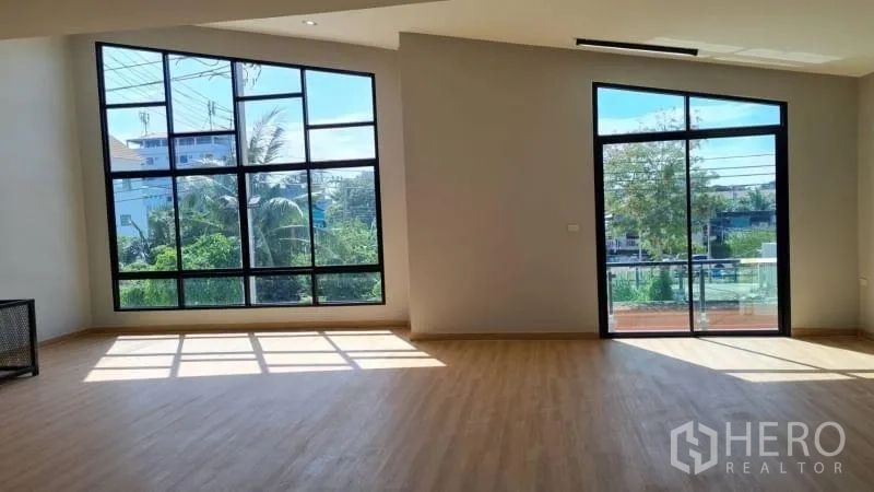 Warehouse for rent in Bang Bua Thong, Nonthaburi - Bright office with floor-to-ceiling windows and a sliding door to a small balcony overlooking greenery.