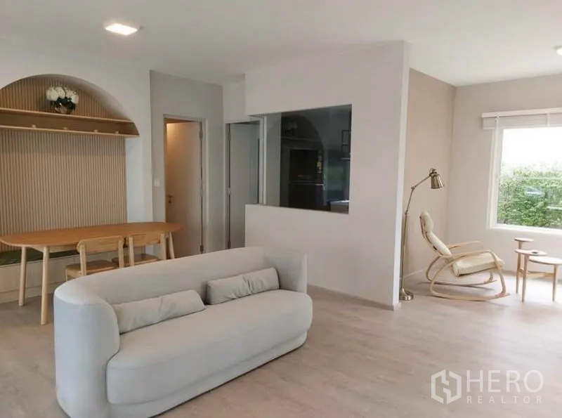 Detached House for rent in Prawet, Bangkok - Open-plan living and dining area with light wood floors, sofa, dining table, and large windows.