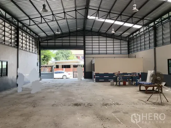 货栈 出售在Pathum Thani - 仓库内部宽敞高挑，混凝土地面，天窗采光，前方卷帘门敞开。