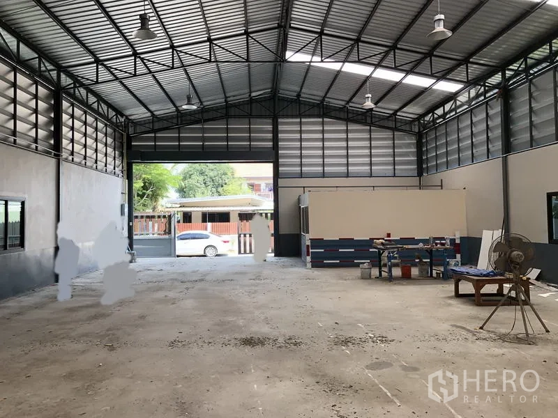 货栈 出售在Pathum Thani - 仓库内部宽敞高挑，混凝土地面，天窗采光，前方卷帘门敞开。
