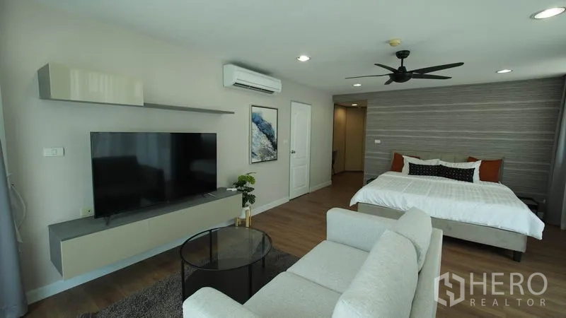 คอนโด ให้เช่าในKhlong San, Bangkok - ห้องนอนมาสเตอร์กว้าง เตียงคิง โซฟานั่งเล่น ทีวีติดผนัง และพัดลมเพดาน