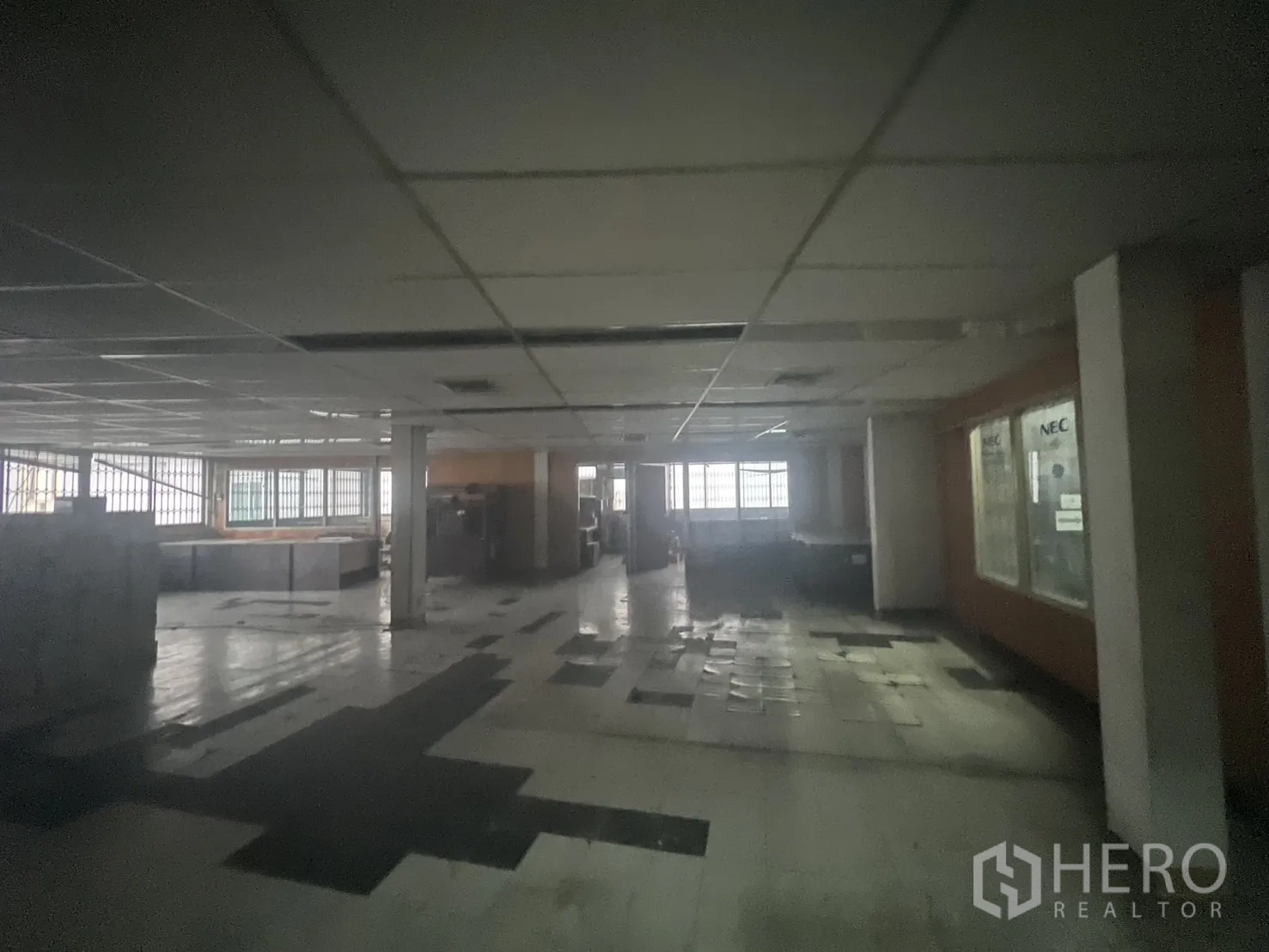 อาคารพาณิชย์ ให้เช่า - ชั้นว่างขนาดใหญ่ ฝ้าเพดานแขวน หน้าต่างลูกกรง และพื้นกระเบื้องเก่า.