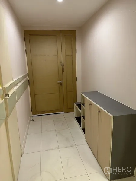 Condominium for rent in Watthana, Bangkok - Entrance hallway with wooden door, shoe cabinet and white tiled floor.