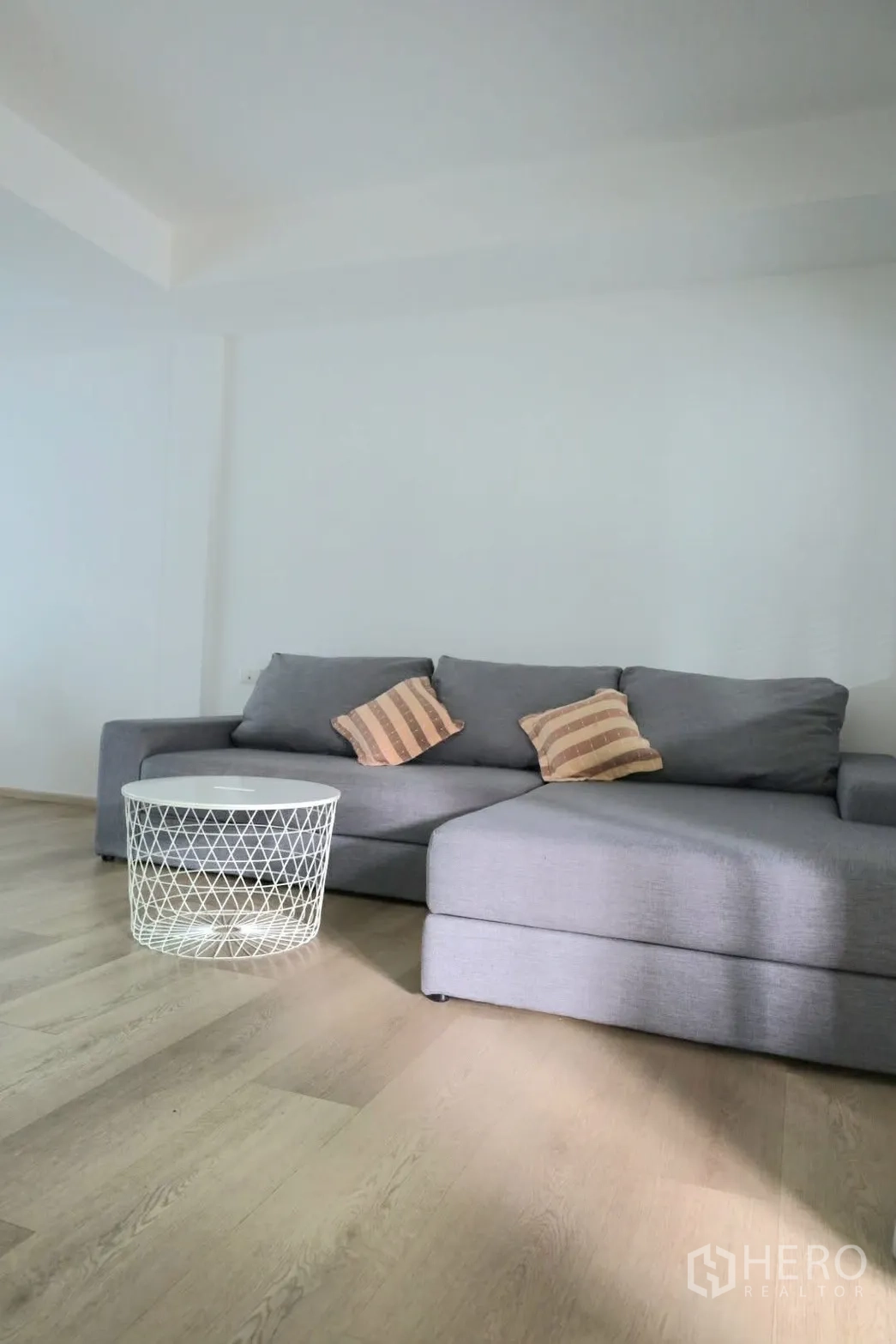 联排别墅 for rent in Prawet, Bangkok - 客厅灰色L形沙发，配白色圆形铁艺茶几。