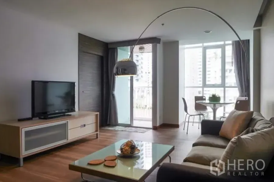 Condominium for rent in Pathum Wan, Bangkok - Bright living room with sofa, TV console, arc floor lamp and a balcony in a Pathum Wan condo near BTS Chitlom.
