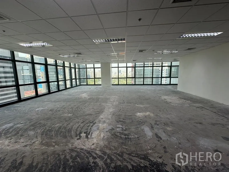 办公空间 出租在Bang Rak, Bangkok - 宽敞未配家具的办公楼层，大窗与中央立柱，眺望曼谷天际线。