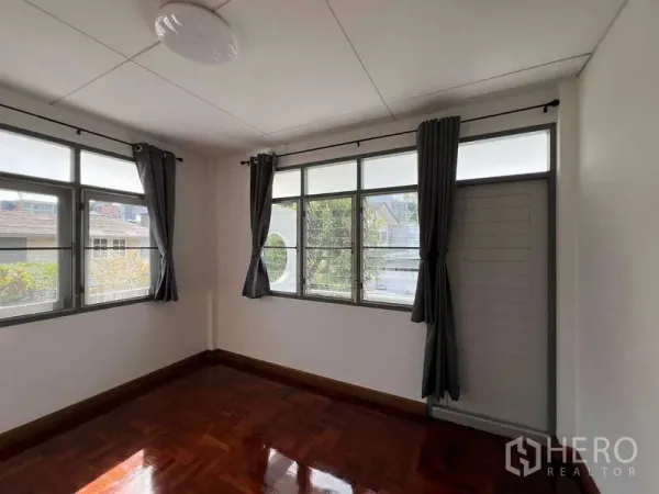 บ้าน ให้เช่าในBang Na, Bangkok - ห้องนอนมุมบ้าน มีหน้าต่างรอบด้าน ผ้าม่านสีเข้ม และพื้นปาร์เกต์