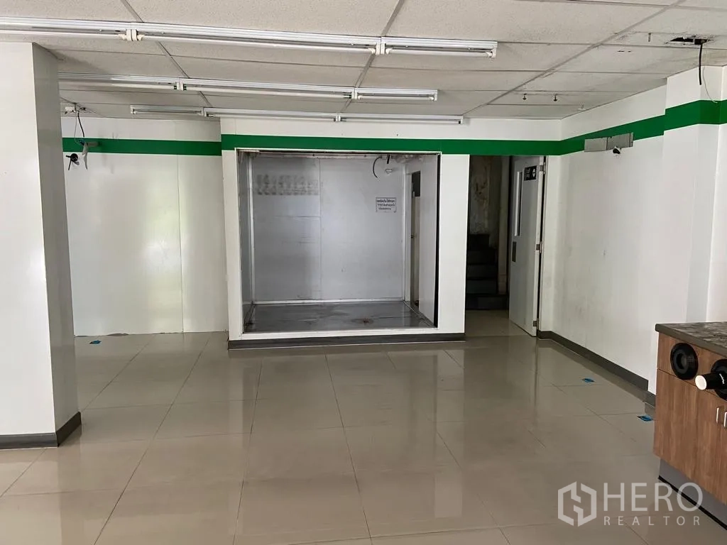 零售空间 出租在Khlong Toei, Bangkok - 前墙展示不锈钢内衬凹位、通往楼梯的门与瓷砖地。