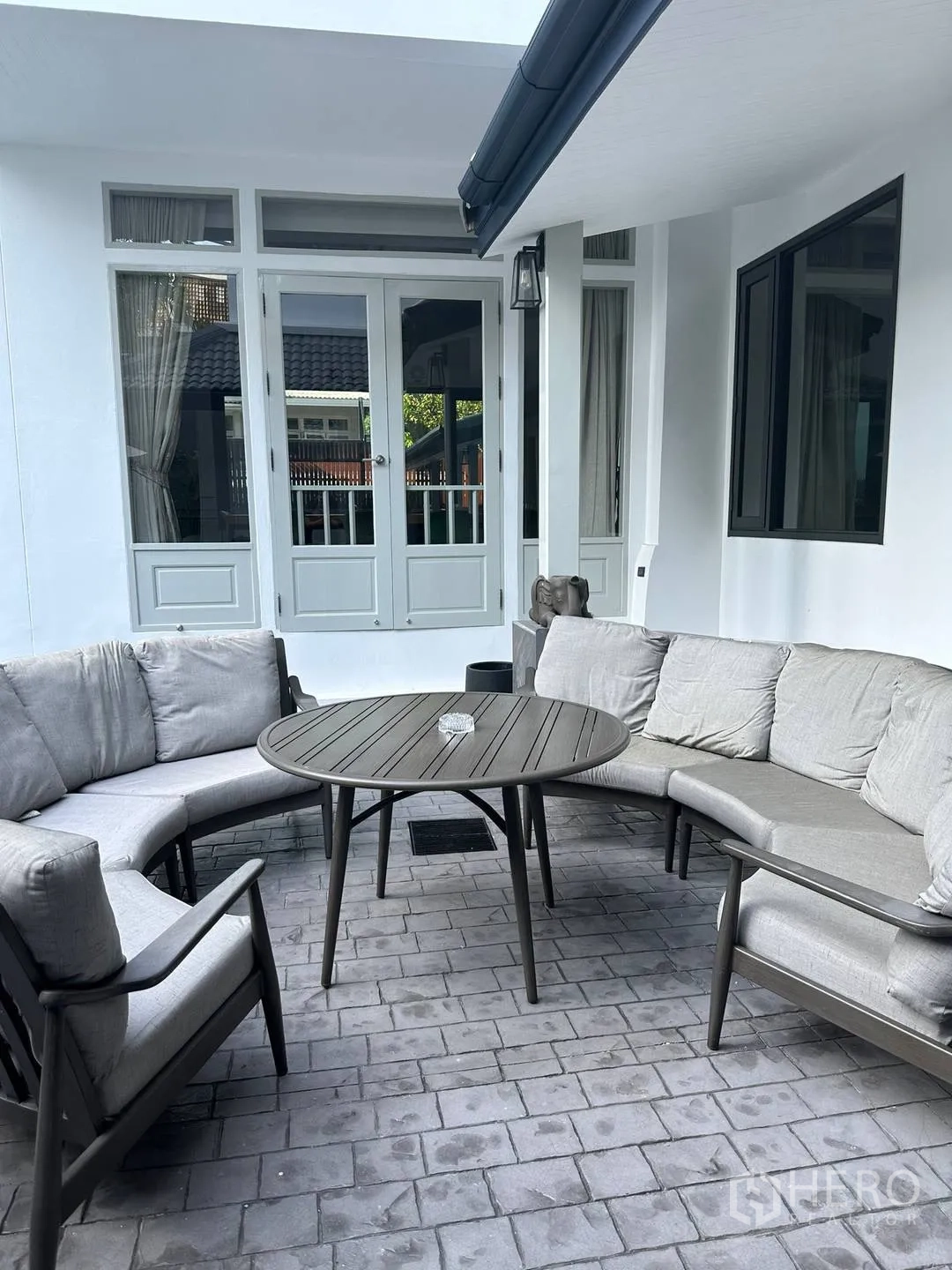 บ้านเดี่ยว for rent in Watthana, Bangkok - มุมนั่งเล่นกลางแจ้งพร้อมโซฟาโค้งและโต๊ะกลมหน้าประตูบานกระจก