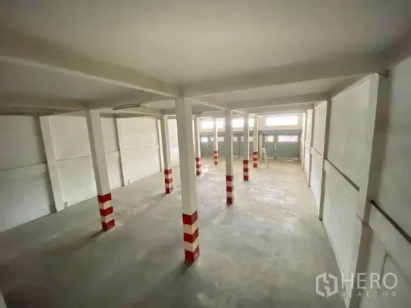 Warehouse for rent in Khlong Toei, Bangkok - Open-plan storage area with multiple support columns, concrete floor, and front roller shutters letting in light.