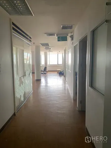 Office Space for rent in Lak Si, Bangkok - Bright corridor with glass-walled meeting room, columns and an exit sign leading to windows.