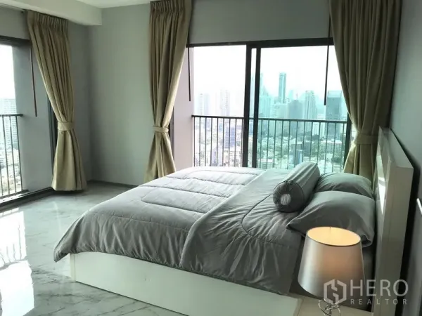 公寓 出租在Khlong Toei, Bangkok - 主卧配落地窗与城市天际线景观的空堤区公寓卧室。