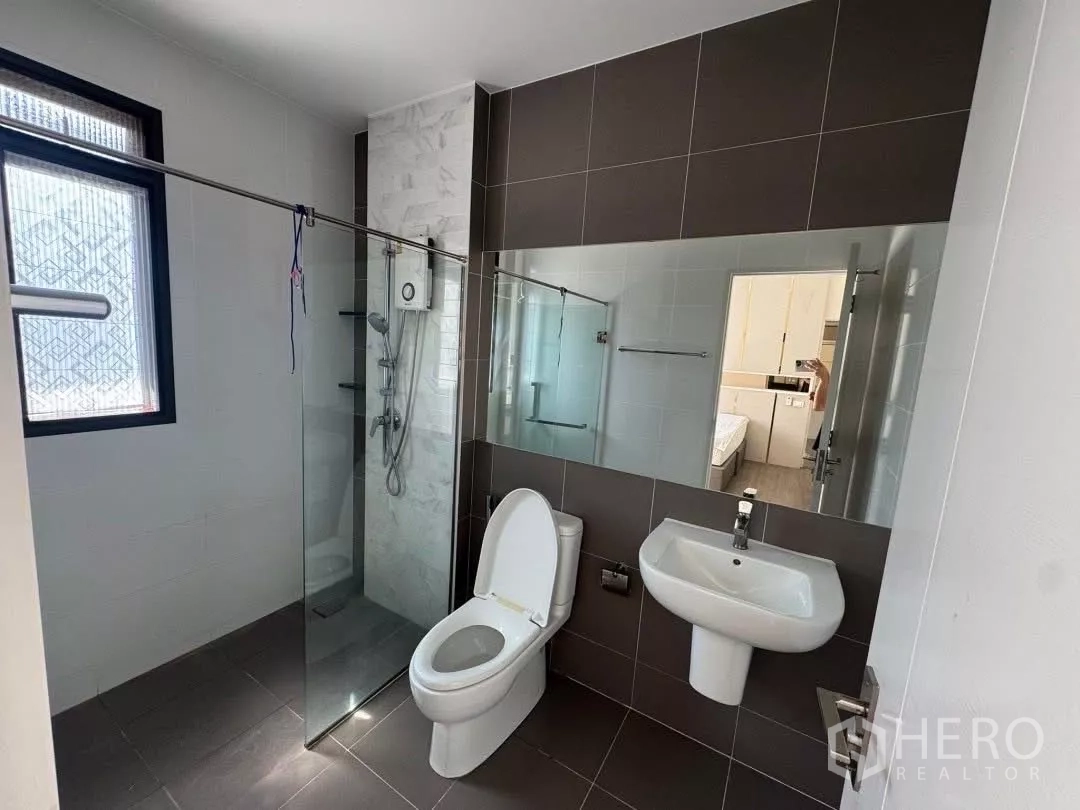 Detached House for rent in Saphan Sung, Bangkok - Bright bathroom with glass-enclosed shower, wall-mounted sink and toilet.