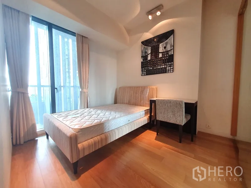 Condominium for rent in Sathon, Bangkok - Second bedroom with large window, balcony access and a study desk.