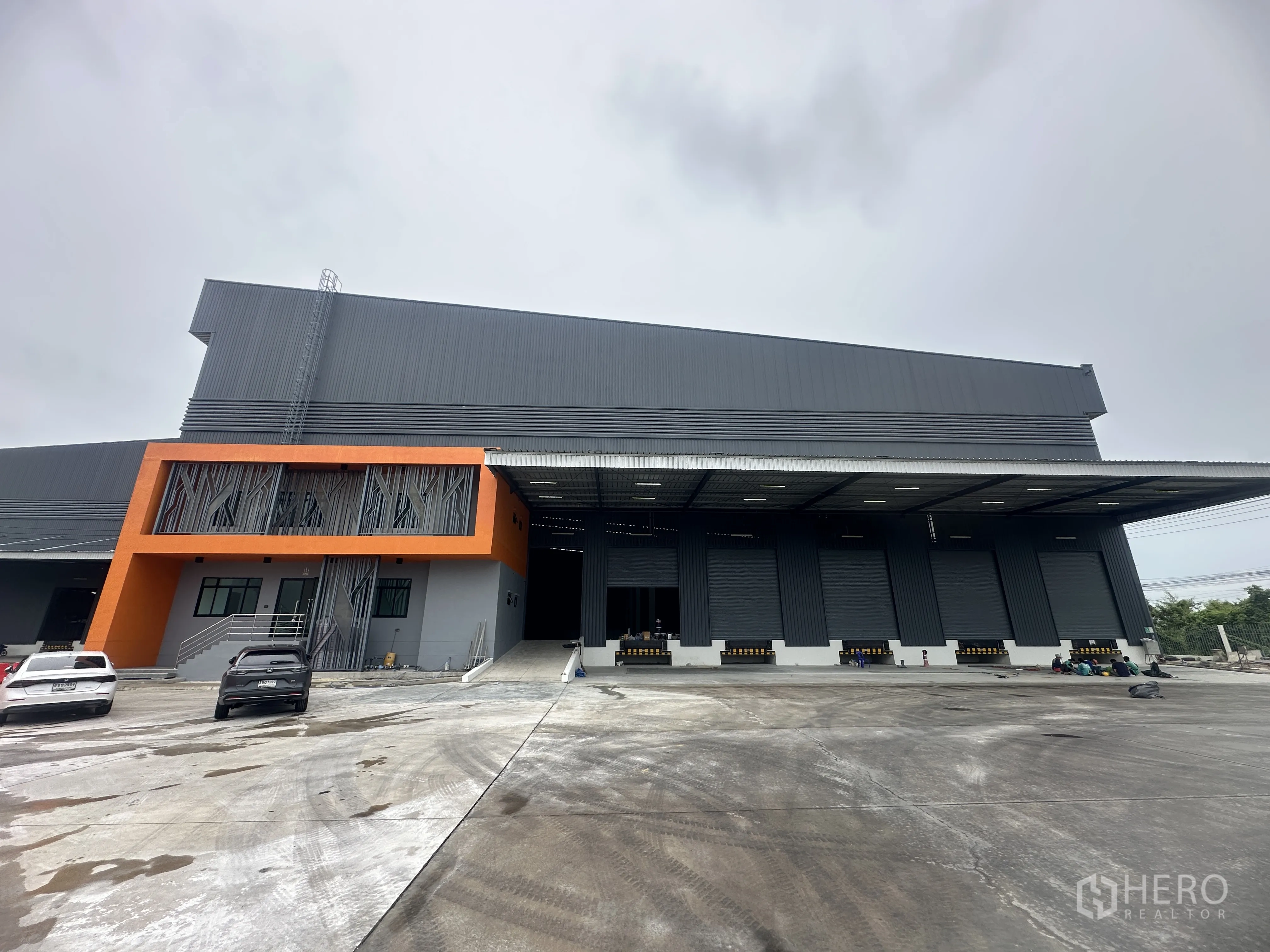 Factory for rent in Bang Phli, Samut Prakan - Modern factory exterior with orange office block, covered loading canopy and wide yard.