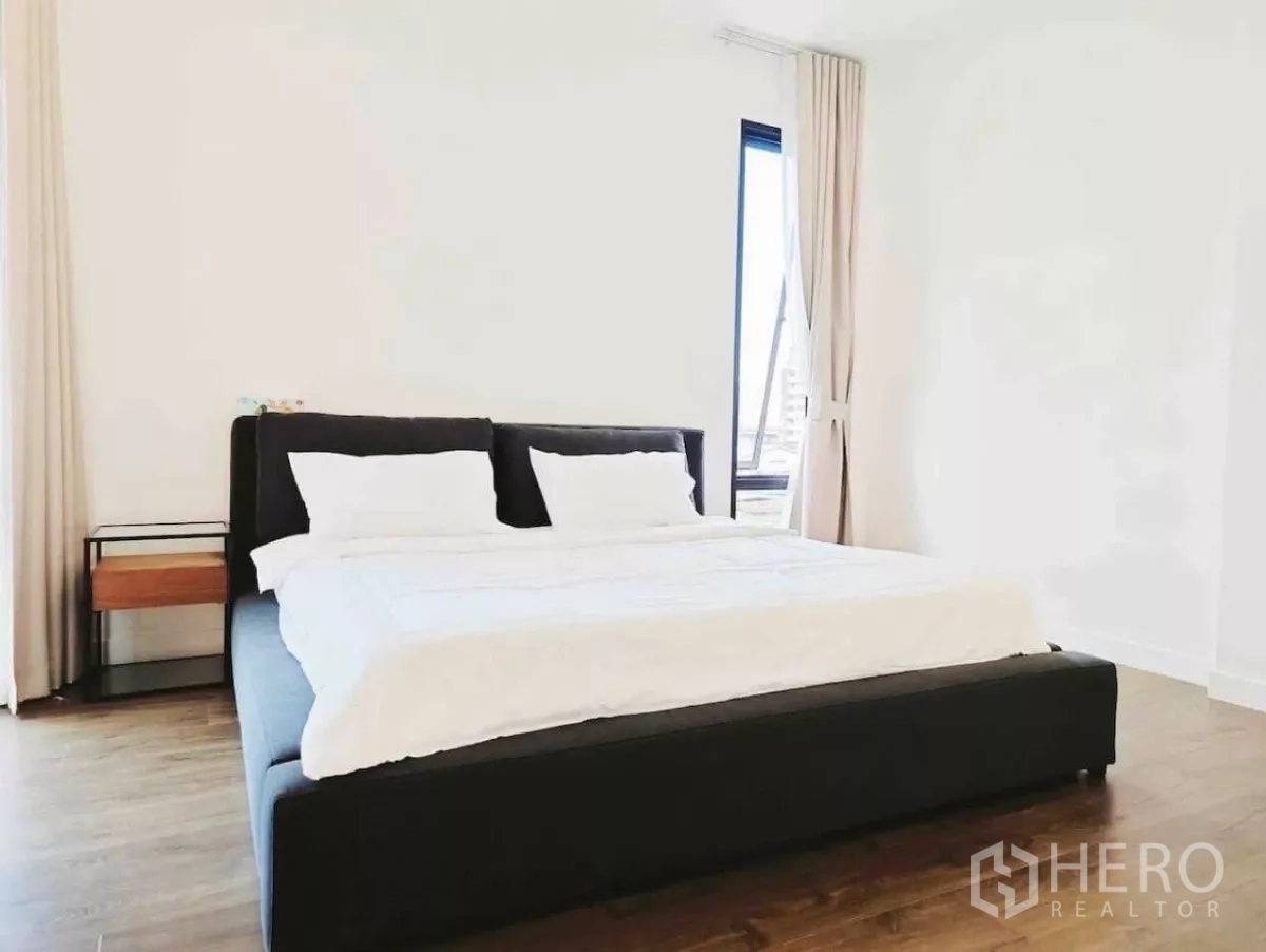 独立式住宅 出租在Phaya Thai, Bangkok - 明亮卧室，黑色软包床、白墙与木地板。