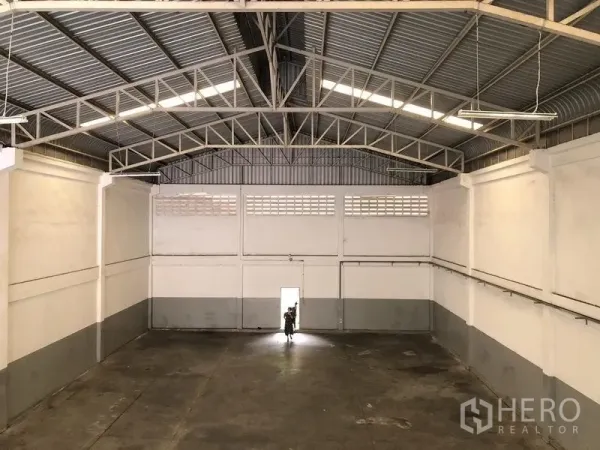 Factory for rent in Pathum Thani - High-clear warehouse bay with steel truss roof and concrete floor.