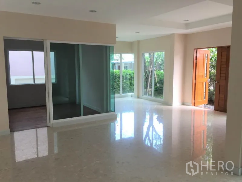 Detached House for rent in Saphan Sung, Bangkok - Bright open-plan living area with glossy floors, large windows and a glass-partition room beside the front door.