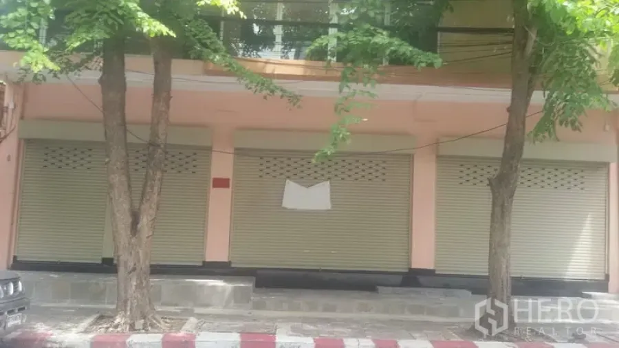 Office Space for rent in Sathon, Bangkok - Street-level building facade in Sathon with three beige roll-up shutters shaded by roadside trees.
