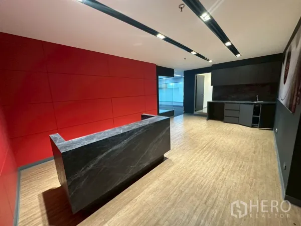 Office Space for rent - Modern reception with marble desk, red accent wall, wood-look flooring and ceiling spotlights.