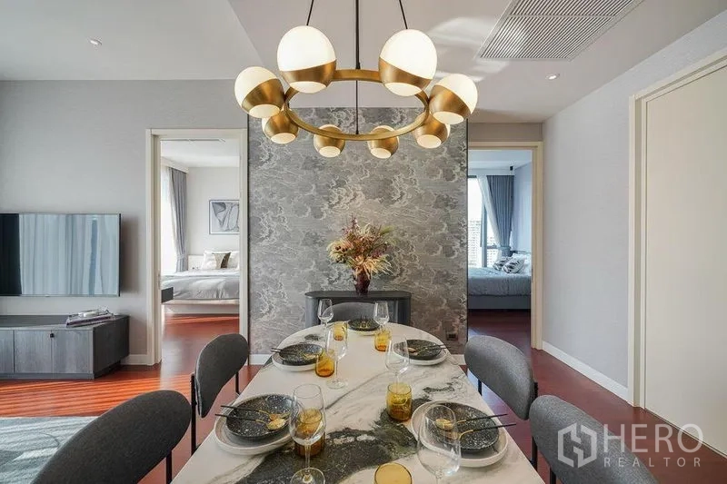 公寓 出租在Watthana, Bangkok - 开放式餐区，椭圆大理石餐桌与醒目吊灯，左右两侧为卧室。