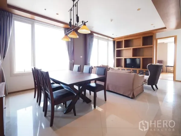 Condominium for rent in Sathon, Bangkok - Open-plan dining and living area with a six-seat table, pendant lights and built-in TV shelving.