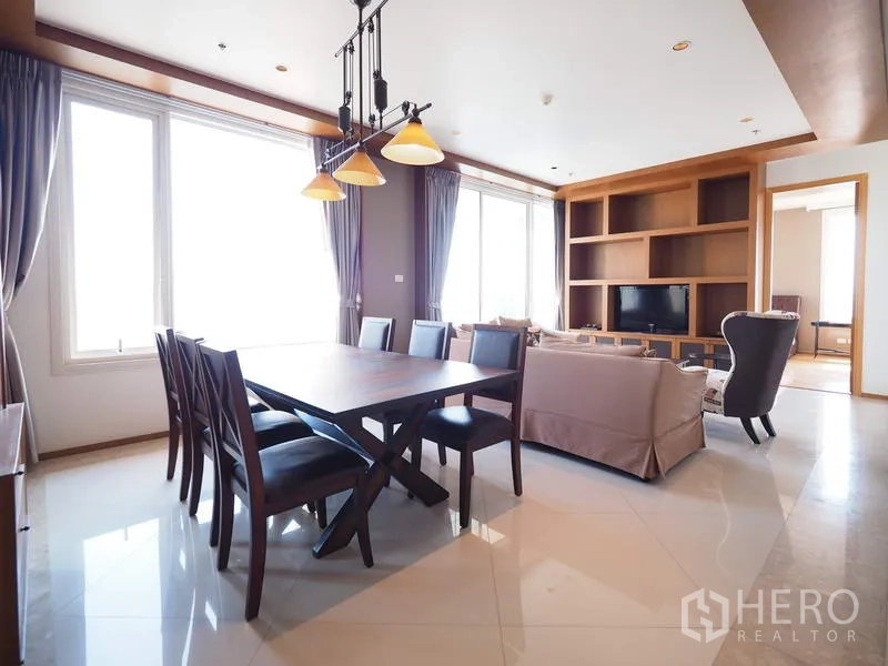 Condominium for rent in Sathon, Bangkok - Open-plan dining and living area with a six-seat table, pendant lights and built-in TV shelving.