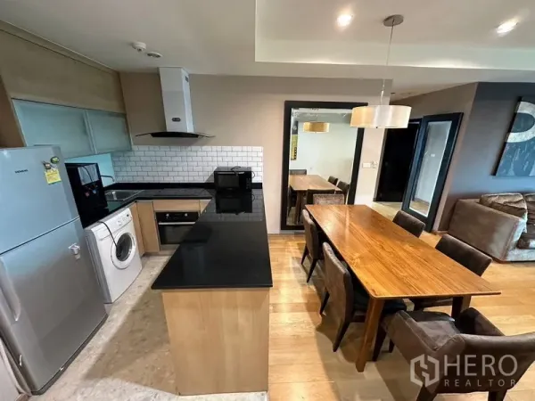 公寓 出租在Sathon, Bangkok - 现代厨房，黑色石材台面岛台，配冰箱、烤箱、洗衣机与餐区