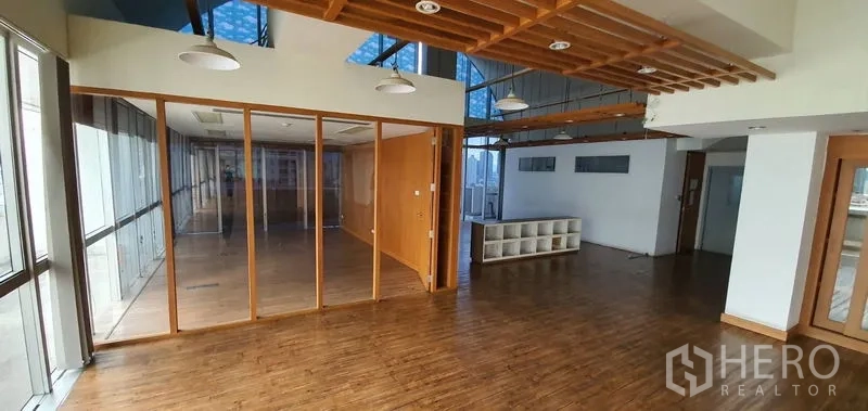 Office Space for rent in Watthana, Bangkok - Open office with glass-partitioned rooms, slatted ceiling details, and abundant natural light.