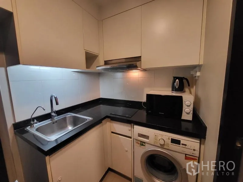 คอนโด ให้เช่าหรือขายในPhaya Thai, Bangkok - ครัวรูปตัวแอลขนาดกะทัดรัด ท็อปหินสีดำ อ่างล้างจาน เตา เครื่องไมโครเวฟ และเครื่องซักผ้า