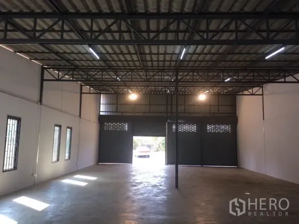 货栈 出租在Pathum Thani - 仓库内部空间开阔，钢架高挑屋顶，水泥地面，设大卷帘门可供车辆进出。