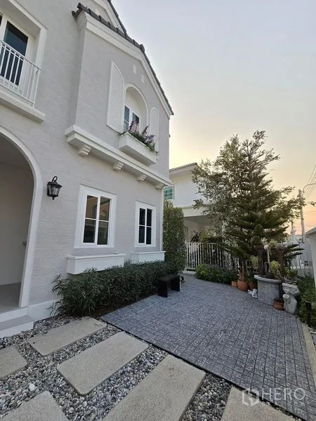 独立式住宅 出租在Bang Phli, Samut Prakan - 前院铺石步道、灌木与拱形门廊的房屋外观。